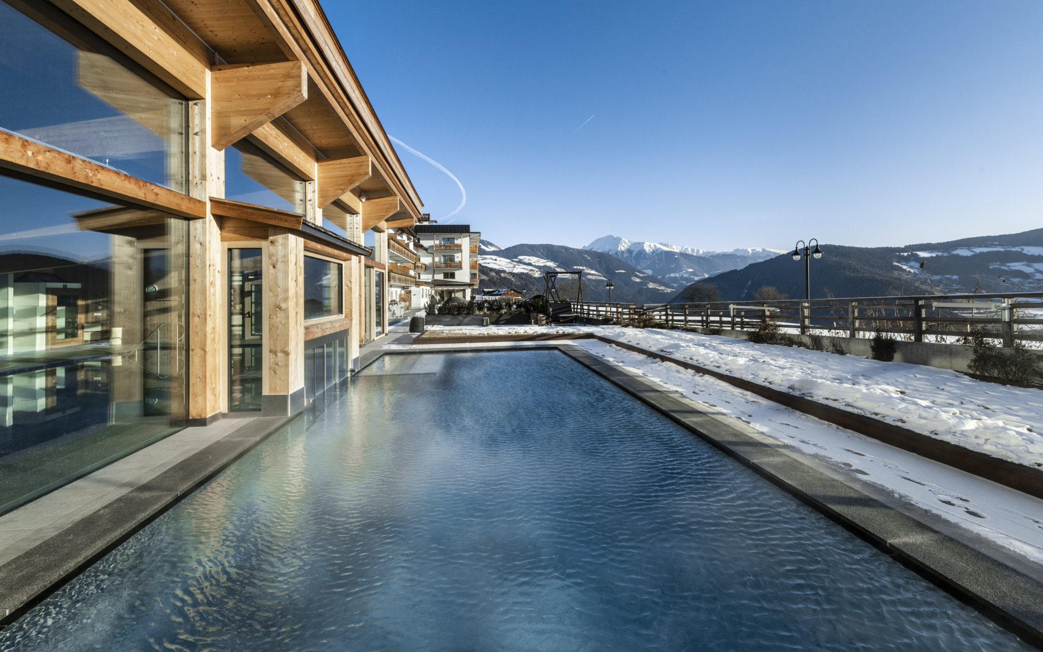 Langer beheizter Infinitypool neben dem Hotel in verschneiter Winterlandschaft
