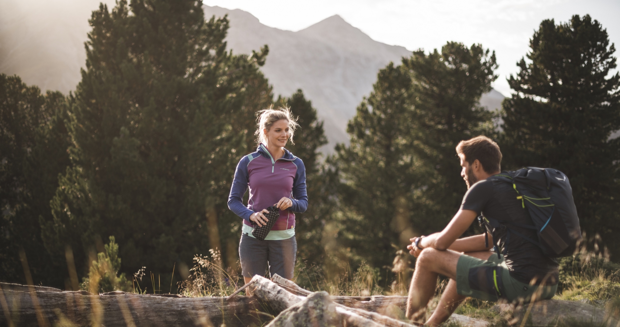 Frau in Sportkleidung bei einer geführten Aktivität in der sonnigen Berglandschaft