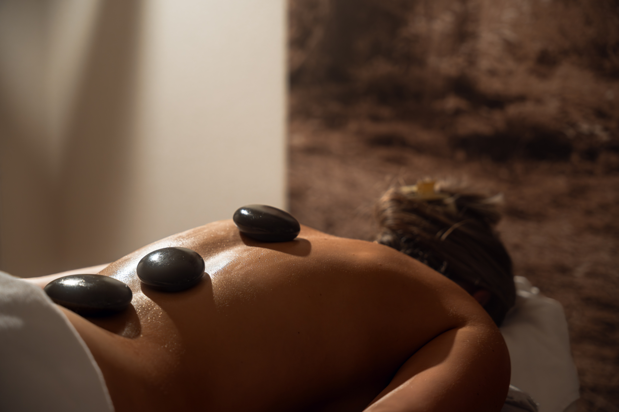 Warme Massagesteine liegen auf dem Rücken einer Person im Wellnessbereich