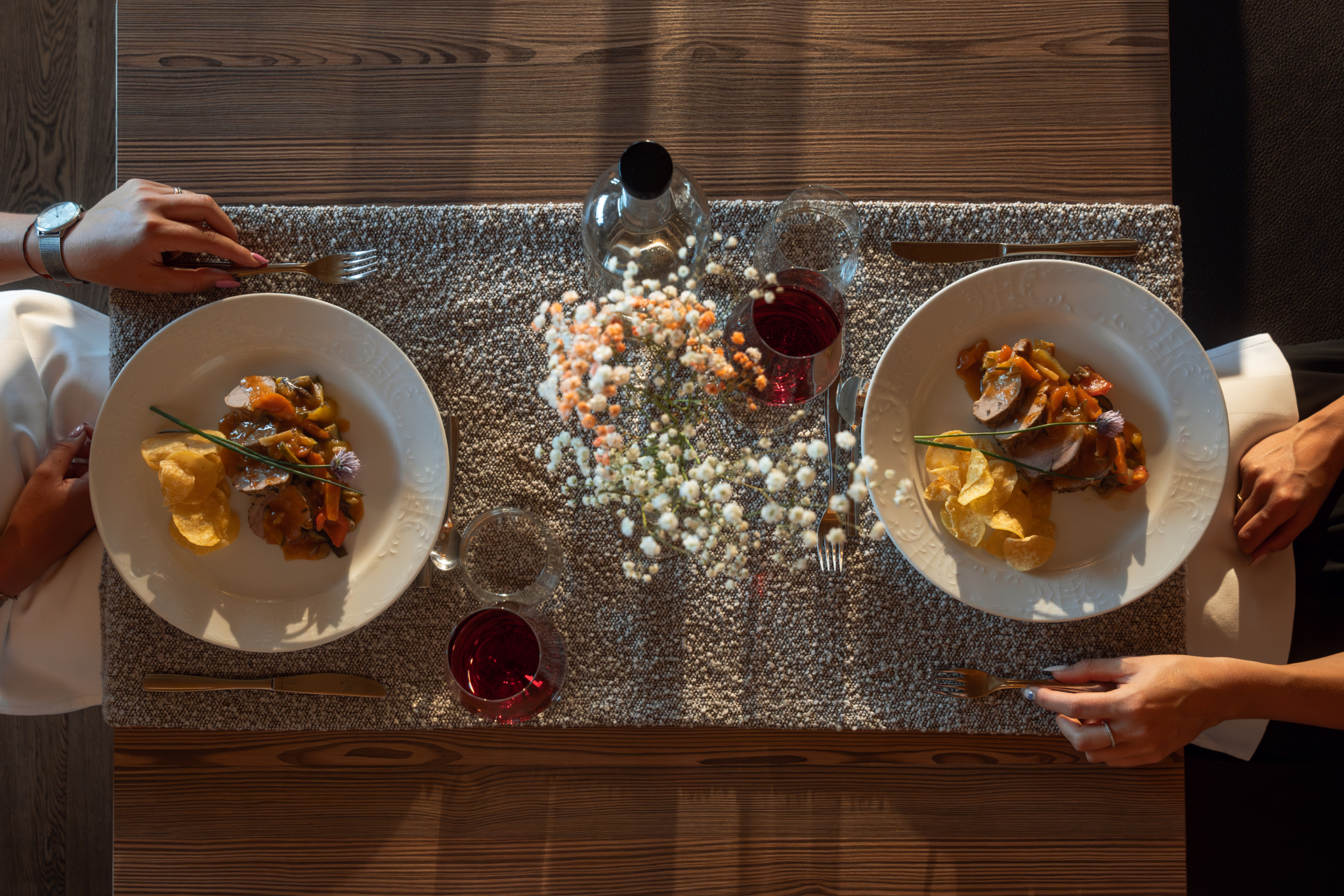 Zwei fein angerichtete Gerichte mit Rotwein und Tischdekoration von oben